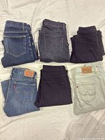 Six folded jeans in two rows showing colour variety and back pocket branding