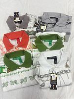Six folded polo shirts showing collars and tags
