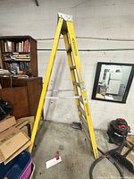 Full view of yellow Werner fiberglass step ladder open in A-frame position