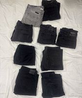 Nine folded pairs of jeans laid out on surface showing color range