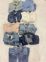 Stack of nine folded denim jackets showing variety of colours and styles