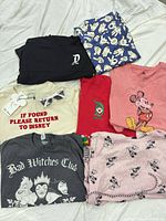 All six shirts laid out plus pink top and grey tee