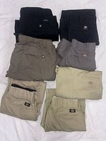 Seven folded pants in assorted colors displayed on white surface