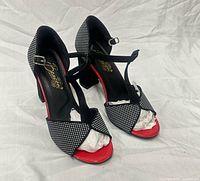 Front three-quarter view showing both shoes, polka-dot toe bands, red toe bed, T-strap design