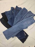 Stack of eight pairs of jeans in various blue and black washes