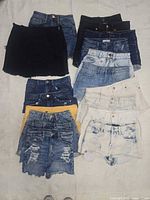 Overview of stacked denim skirts and shorts on white background