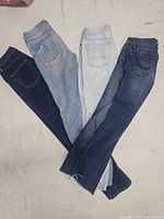 Four pairs of jeans fanned out showing front legs and washes