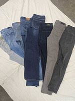 Stack of eight jeans showing variety of washes and colors
