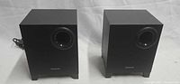 Front view of both Creative A220 subwoofers showing ports and logo