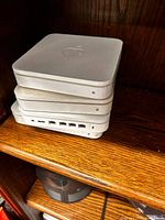 Three stacked Apple AirPort Extreme base stations showing top Apple logos and front LEDs