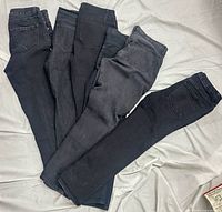 Five pairs of black jeans layered showing overall condition