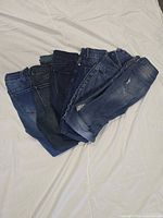 Six folded jeans stacked showing variety of washes