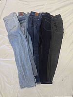 Five pairs of jeans laid flat showing variety of washes
