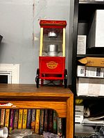 Front view of Nostalgia red popcorn cart on shelf