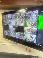 Front view of Sharp TV displaying multiple security camera feeds while wall-mounted