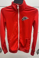Front view of red Nike track jacket on hanger