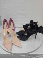 Group view of three visible pairs: fuchsia pumps, blush clear pumps, black bow sandals