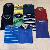 Front view of all ten polo shirts laid flat showing colours and logos