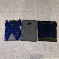 Three folded Banana Republic V-neck sweaters blue argyle, grey, navy with green stripes