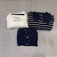 Three folded polo shirts white, striped, dark navy