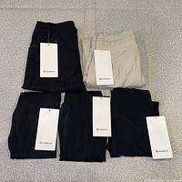 Front view of five folded Lululemon pants/leggings showing hangtags