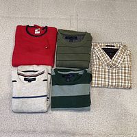 All five folded sweaters displayed on flat surface