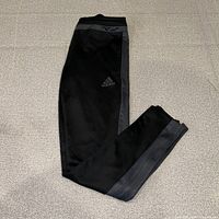 Full view of folded black Adidas jogger pants