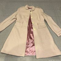 Full view of pink tweed coat laid flat open to show lining