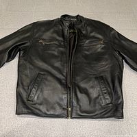 front view of black leather jacket laid flat showing pockets and zipper