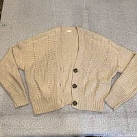 Full view of beige knit cardigan laid flat
