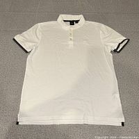 Full front view of white Hugo Boss polo laid flat