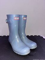 Front three-quarter view of both light blue Hunter rain boots showing logo and overall condition
