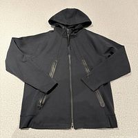 Front view of black Jordan tech hoodie laid flat showing full design