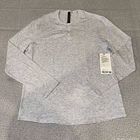 Full view of heather grey long-sleeve henley laid flat showing front and tag