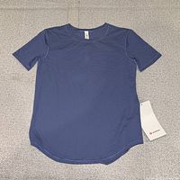 Full view of blue Lululemon tee laid flat showing front and curved hem