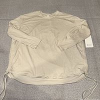 Full view of beige long sleeve top with tag visible