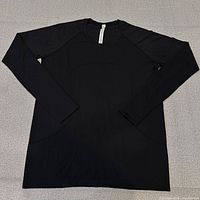 Full view of black long-sleeve top laid flat