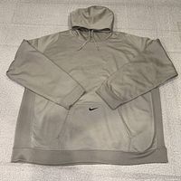 Front view of grey Nike ThermaFit hoodie laid flat