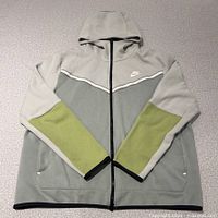 Front view of hoodie laid flat showing color-block, zipper, logo, pockets