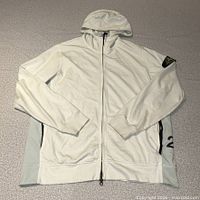 Front view of Stone Island off-white zip hoodie showing hood, central zip, sleeve badge, side graphic
