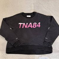Front view showing pink TNA84 graphic and cropped cut
