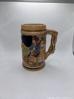 Front view of ceramic stein showing figural relief and handle