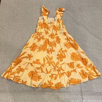 Full view of dress laid flat showing print, straps, tiered skirt