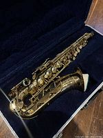 Alto saxophone resting in blue plush interior of Conn hard case