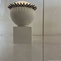 Front view of white spherical maquette on plinth with metal spike crown