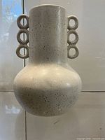 Front view of white speckled ceramic vase showing full shape and loop handles