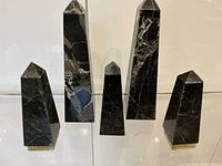 Front view of all five marble obelisks showing size differences and brass bases