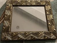 Front view of mirror showing full gold patterned frame and mirror glass