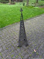 Full view of metal lattice obelisk on driveway