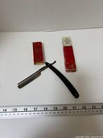 Straight razor opened beside ruler with two-piece red box